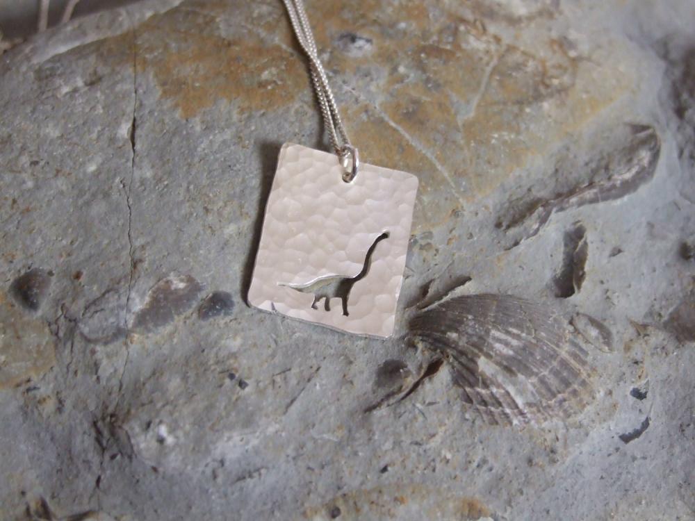 Silver Dinosaur Pendant: A Textured Sterling Silver Pendant Showing A Silhouette Of Long Necked Dinosaur.